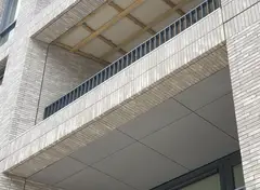 Balkon van een gebouw met lichte baksteen en metalen balustrade.