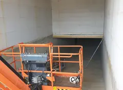 Ruimte in ruwbouwfase met bouwlift.