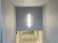 Ingang van een modern gebouw met een gebogen plafond van gevelplaten en een groene deur- en raamomlijsting.