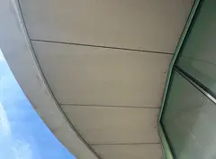 Interieur van een betonnen doorgang met lichte wand- en plafondplaten, verlicht door een verticale LED-lamp.