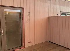 Muur van verticale composietpanelen bij terras en balkondeuren.