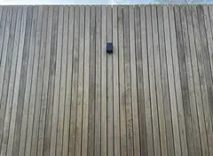 Houten gevel van verticale latten met sensor in het midden van de muur.