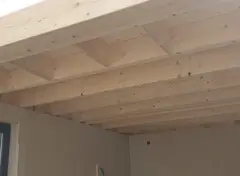 Interieur van een gebouw met zichtbare houten draagbalken.