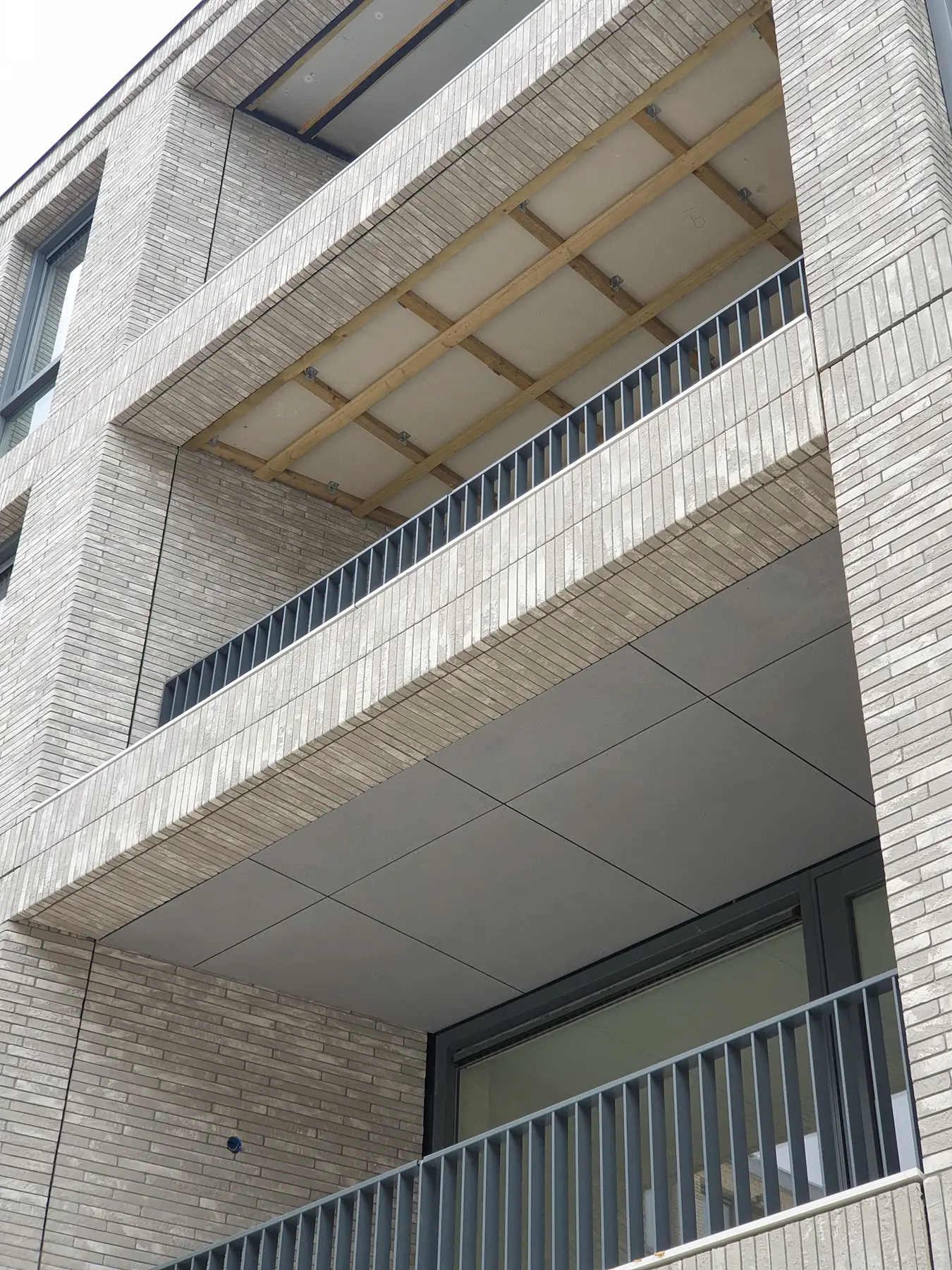 Balkon van een gebouw met lichte baksteen en metalen balustrade.