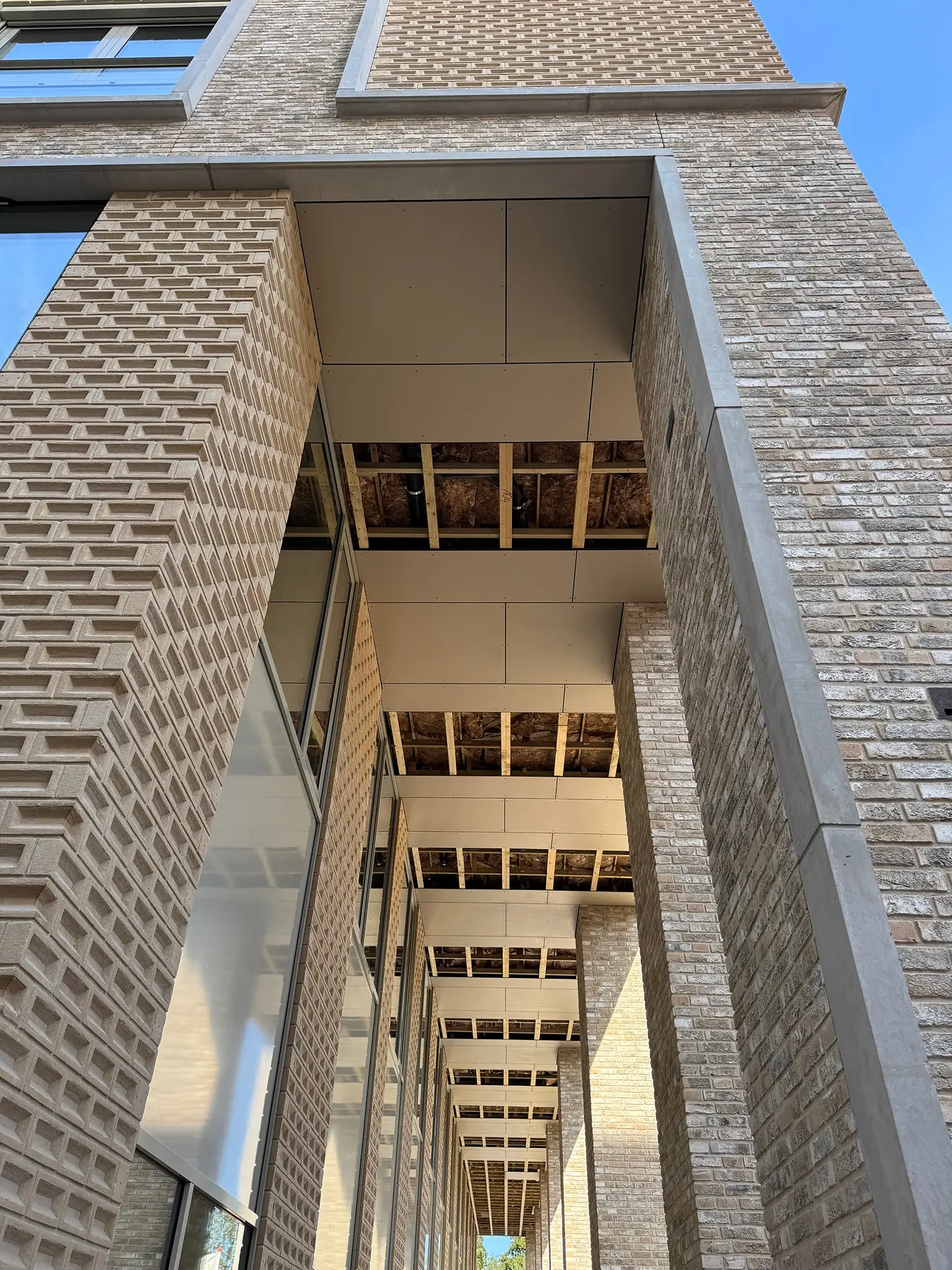 Overdekte doorgang met gevel van lichte baksteen tijdens montage van plafonds.