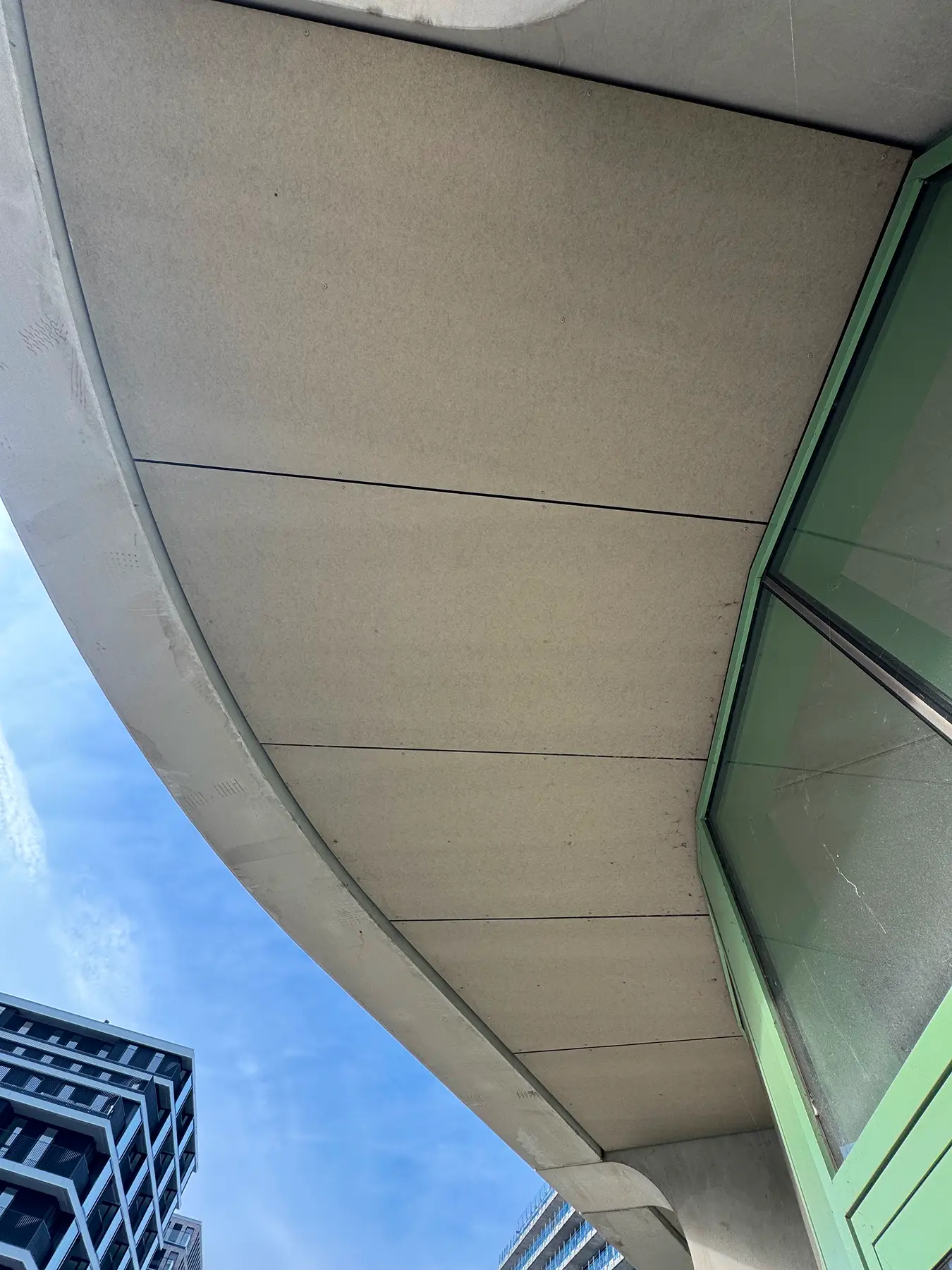 Interieur van een betonnen doorgang met lichte wand- en plafondplaten, verlicht door een verticale LED-lamp.