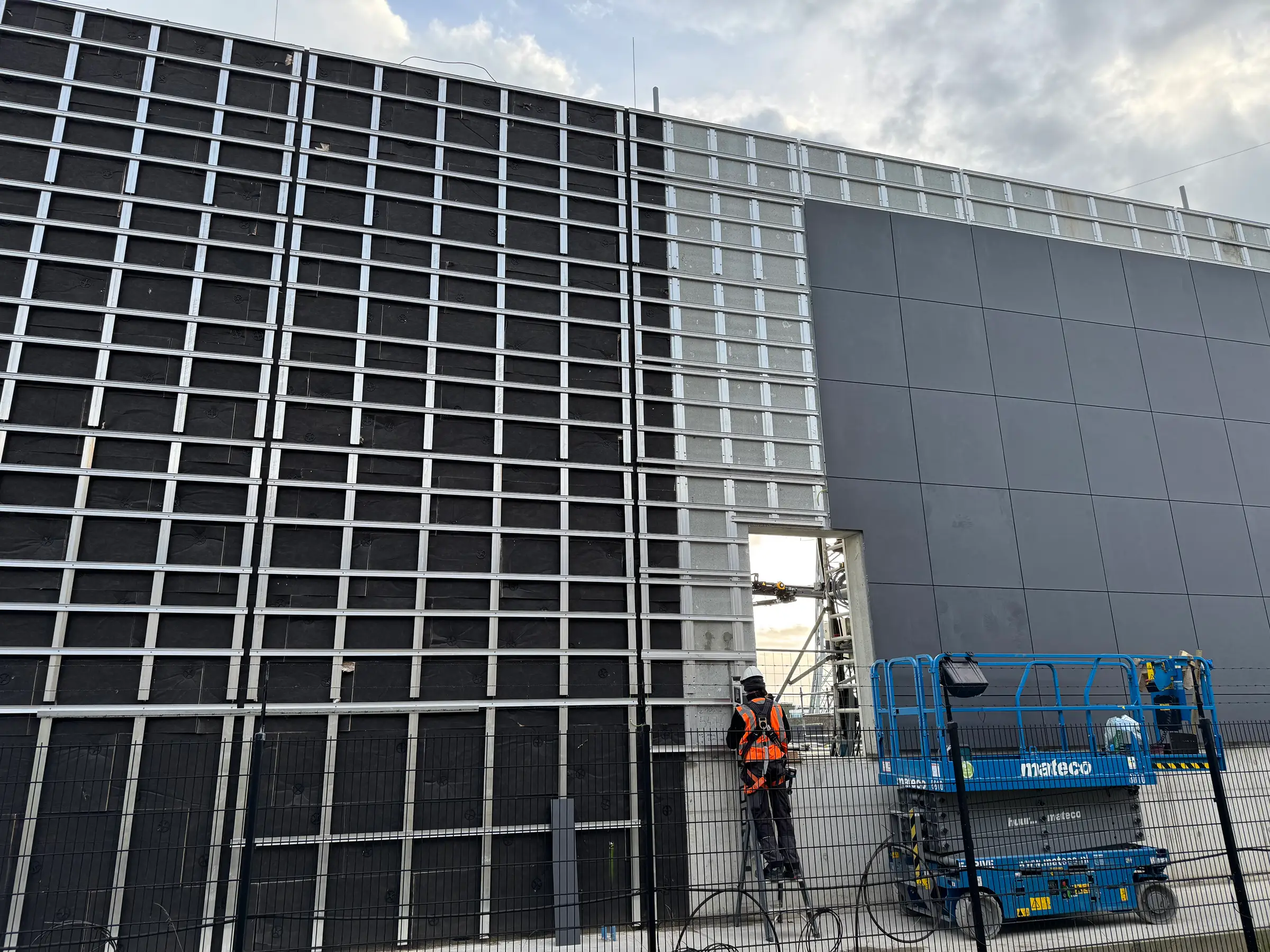 Montage van een geventileerde gevel met donkere gevelpanelen.