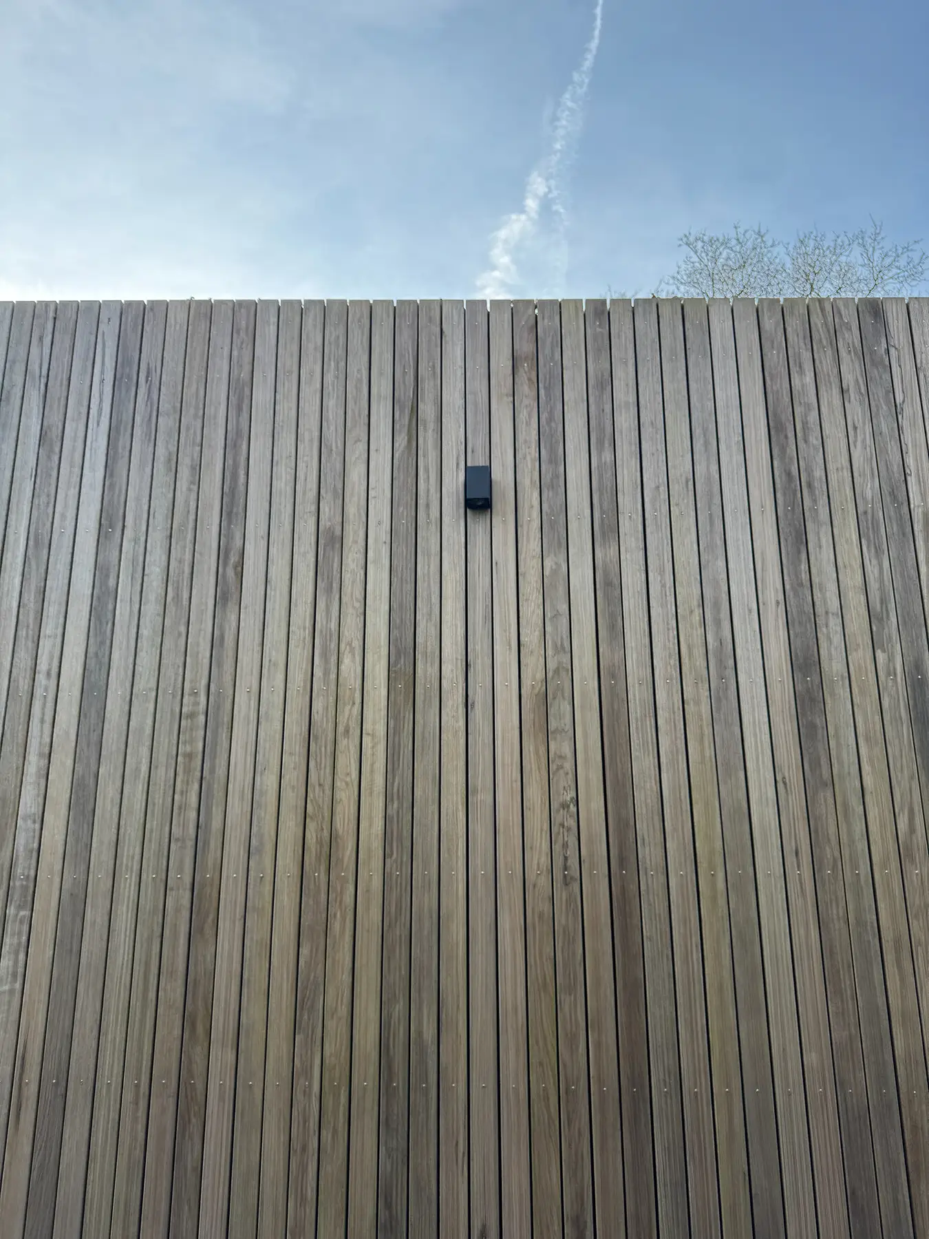 Houten gevel van verticale latten met sensor in het midden van de muur.