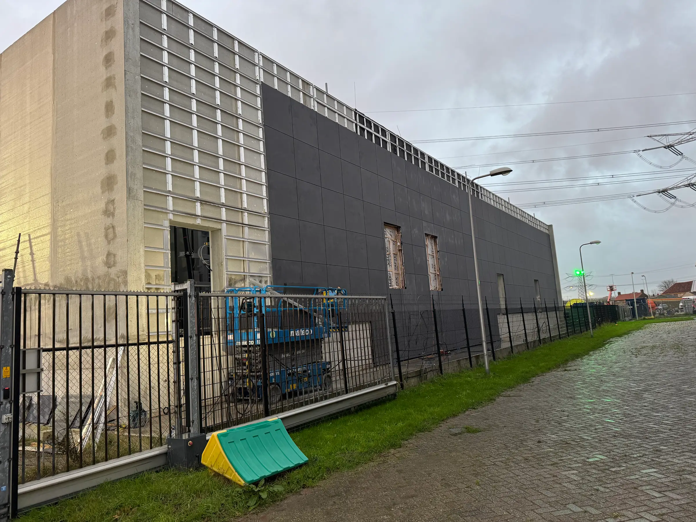 Gebouw in aanbouw met montage van donkere gevelpanelen.