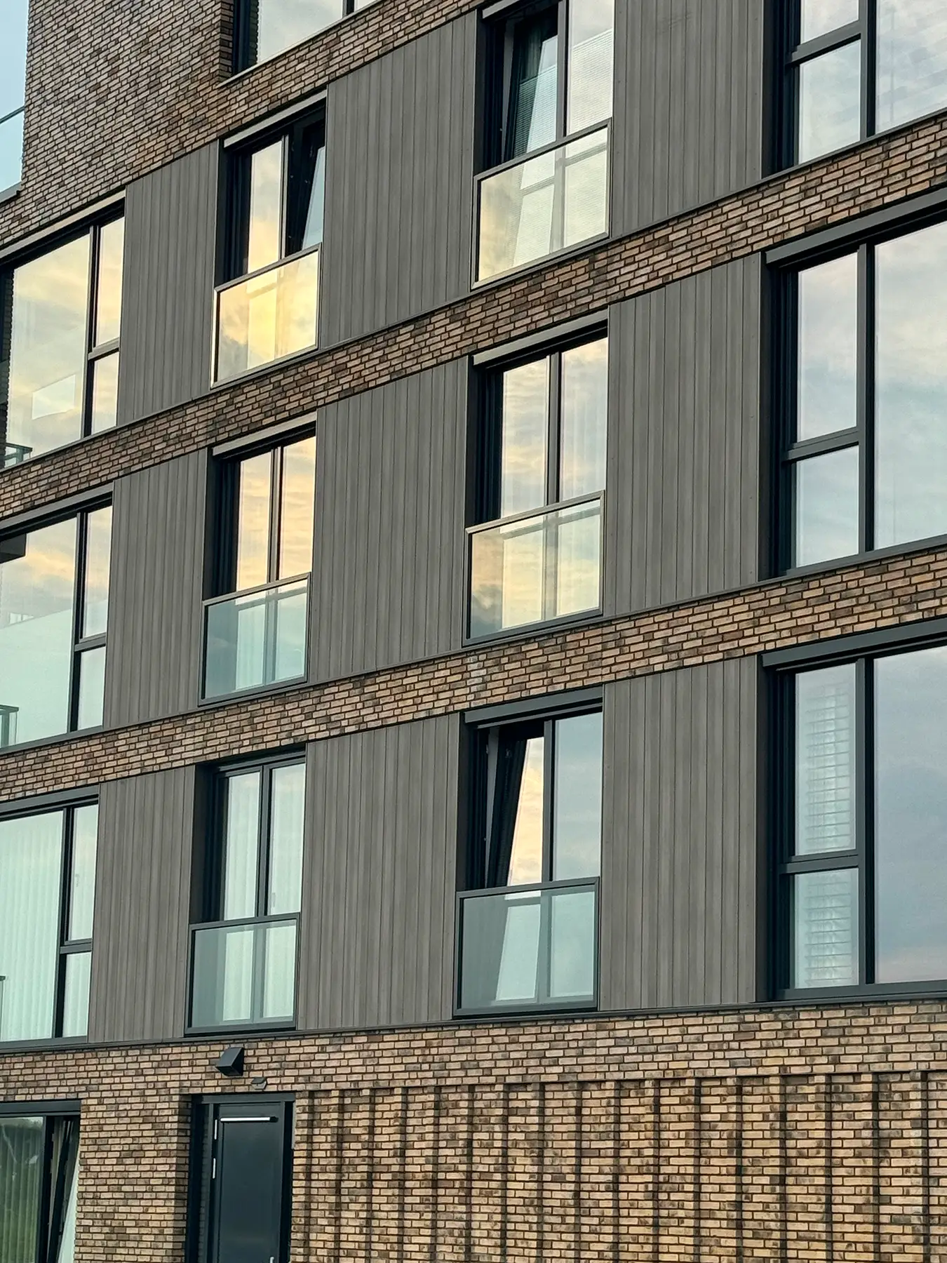 Modern gebouw met gevel van baksteen en grijze panelen.