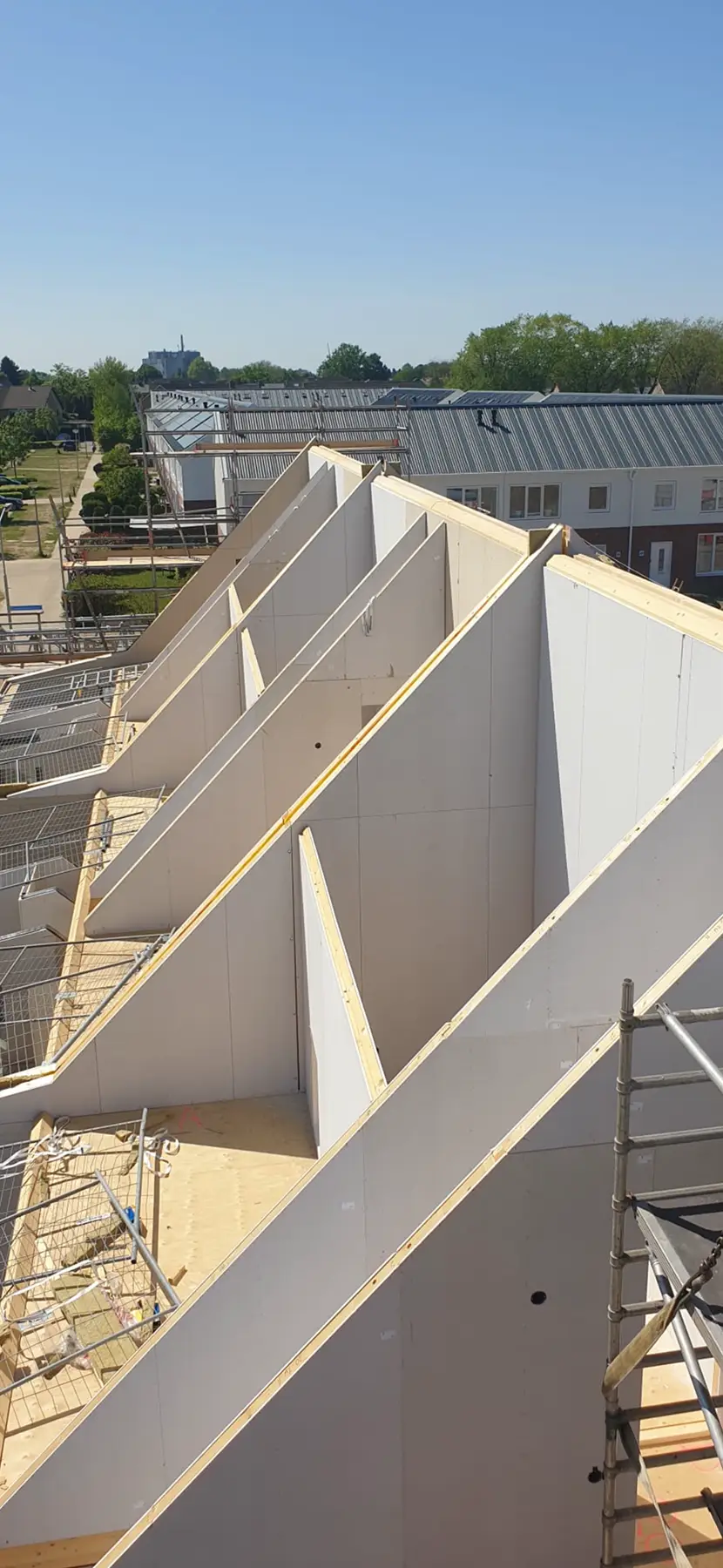 Schuine prefabwanden die de dakvorm vormen van een gebouw in aanbouw.