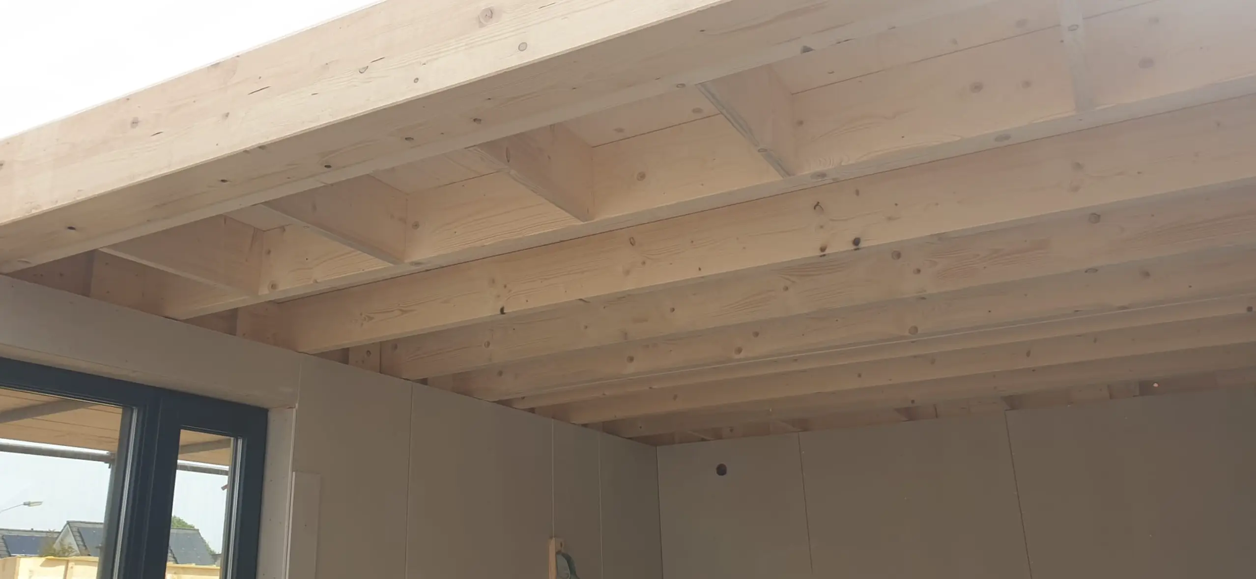 Interieur van een gebouw met zichtbare houten draagbalken.